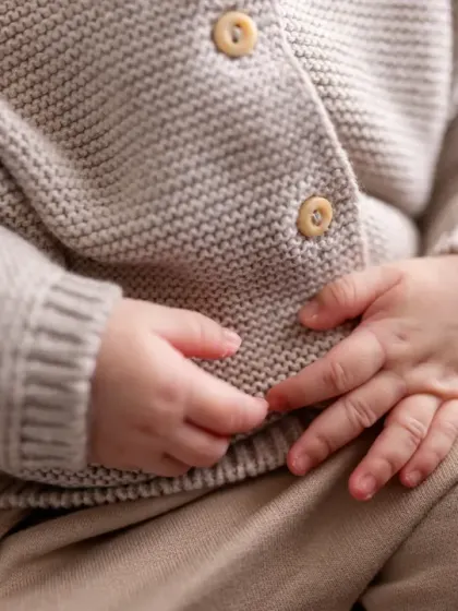 A close-up on the newborn's tiny hands and cozy knit cardigan. I love focusing on these little details that tell the story of this new life.