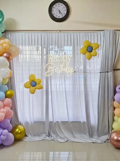 A lovely sunflower-themed decoration for a first birthday, using a pastel balloon garland with large, crafted balloon daisies.
