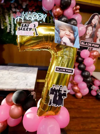 A close-up of the personalized details for a Blackpink themed party, including a custom photo on the age balloon.