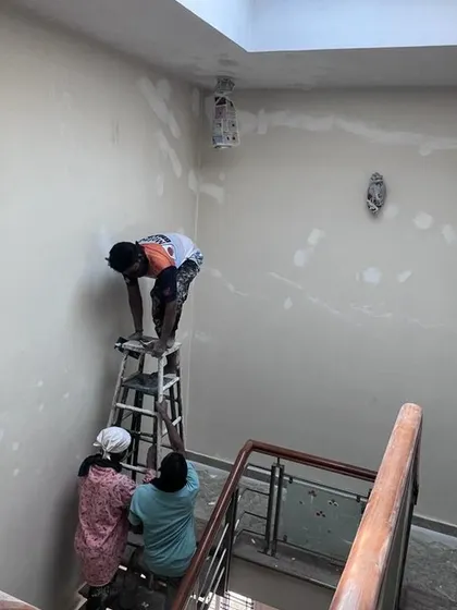 Teamwork is essential for a perfect finish. In this photo, my painters are working together on a staircase wall, with one on a ladder for the higher sections while others assist, ensuring safety and quality.