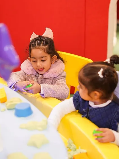 Two young guests deeply engaged in a creative activity. Our hands-on workshops, like this kinetic sand table, are designed to foster focus, creativity, and collaborative play.