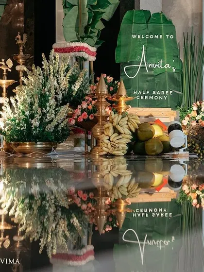 The entrance to a half-saree ceremony, adorned with fragrant jasmine garlands and banana leaves. The reflection on the polished floor doubles the beauty of this traditional South Indian decor.