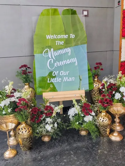 A welcome sign for a naming ceremony, featuring banana leaves and fresh flowers.
