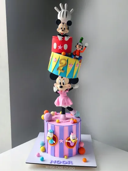 A Minnie Mouse themed topsy-turvy cake that is as playful as it is impressive. This design features multiple characters from the Mickey Mouse universe in a fun, gravity-defying stack.