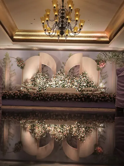 The reflection of a beautifully lit floral stage on a glossy floor, adding a layer of glamour to the reception.