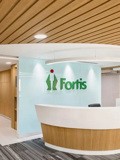 A focused shot of the Fortis Ludhiana reception desk, highlighting its curved form and the backlit brand logo. The design is both functional for staff and welcoming for patients.