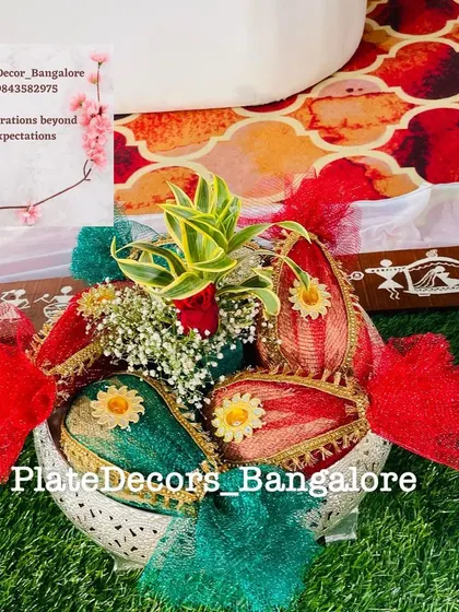 A heart-shaped basket holding decorated coconuts, adorned with red and green ribbons and flowers. A lovely presentation for gifting.