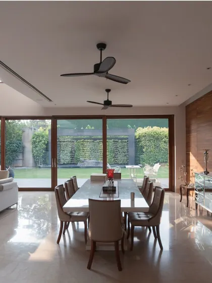 The expansive dining area seamlessly merges with the outdoors through floor-to-ceiling glass walls. This design choice floods the space with natural light and creates a constant dialogue between the interior and the lush landscape.