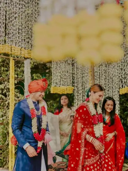 A candid moment of a couple during their daytime wedding ceremony, framed by the beautiful marigold decor.