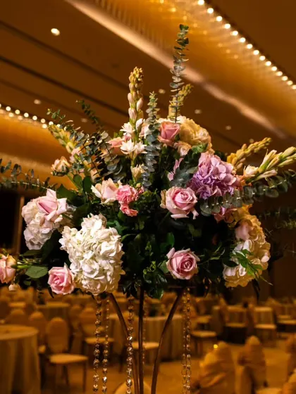 A tall, elegant centerpiece designed for guest tables at a reception. The arrangement features a mix of pink and white hydrangeas and roses, adding a touch of sophistication to the ballroom.