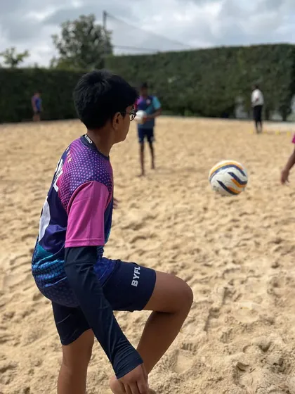 A player practices his first touch on the sand, a difficult skill that builds exceptional ball mastery.