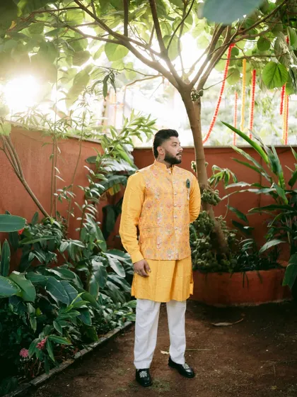 A full-length portrait of the groom in his traditional Haldi outfit, looking ready for the festivities.