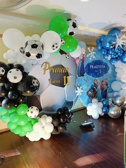 A close-up on the football-themed side of the decoration, with a giant football backdrop and a green, black, and white balloon arch.