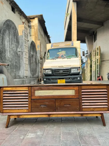 A front-on view of the TV console, highlighting its retro design and practical features for storing media devices.