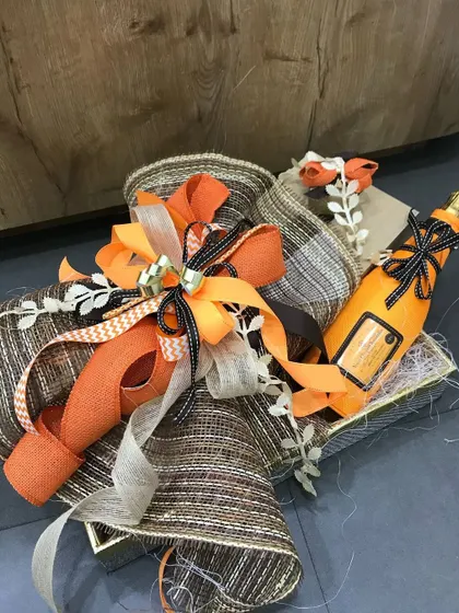 A rustic yet refined hamper featuring a vibrant orange color scheme. We've combined burlap-textured ribbons with bright orange accents and a decorative bottle, creating a gift that is perfect for a daytime celebration or a countryside wedding.