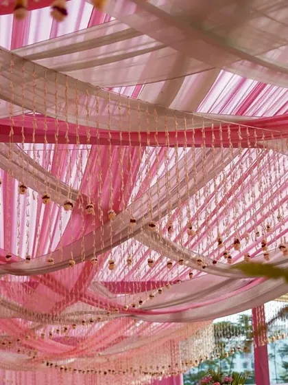 A look at the ceiling decor, with layers of pink and white fabric creating a soft, draped canopy. Delicate floral strings are hung between the drapes, adding another layer of beautiful detail.