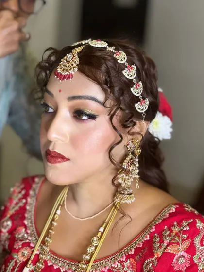 This shot highlights the dramatic eye makeup and bold red lip. It's a powerful and confident bridal look, perfect for the modern bride.