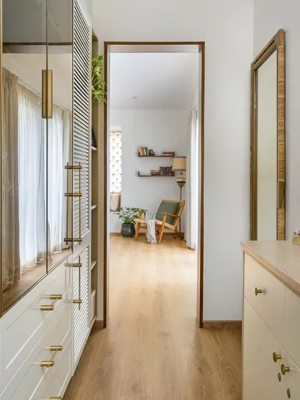 The primary walk-in closet in 'House of Kismish' combines elegant PU and tinted glass shutters, overlooking a charming bay window niche.