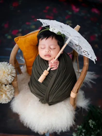 A variation of the parasol theme, with the baby swaddled in a dark green wrap, creating a lovely color contrast.