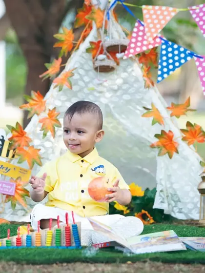 A happy smile from inside our autumn-themed tent setup. I use colorful banners, leaves, and toys to create an engaging environment for your child's photoshoot.