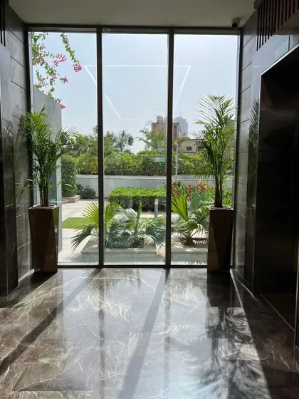 We frame views and soften modern architecture with carefully placed plants. These two palms in an elevator lobby create a beautiful transition between the sleek interior and the lush garden visible outside.