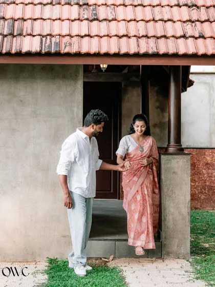 A gentlemanly gesture as the groom-to-be helps his partner down a step, captured in front of a traditional house.