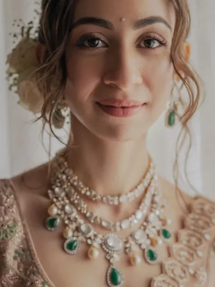 A close-up of a bride with a very soft, minimal makeup look. Fresh skin, a touch of mascara, and a natural lip color let her beautiful features and stunning jewelry take center stage.