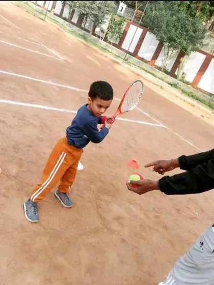 A coach demonstrating the contact point for a forehand shot to a young student. Visual cues are very important for beginners.