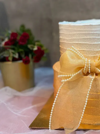 A detail shot of the beautiful sheer bow with pearl strands, adding a touch of softness and elegance to this minimalist two-tier cake.