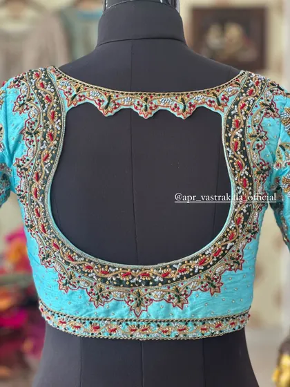 Showcasing an intricate back design on a mannequin. This light blue blouse features a scalloped cutout framed with dense floral embroidery, demonstrating my commitment to detailed craftsmanship on every part of the garment.