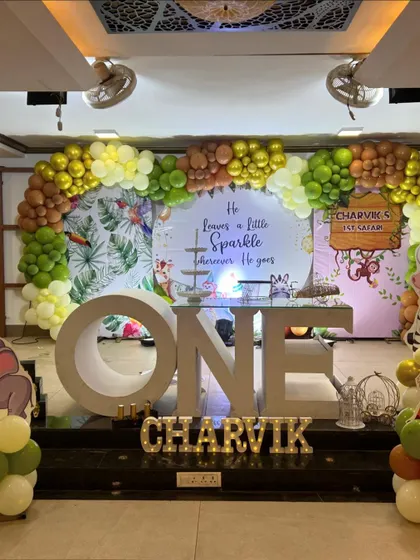 A full view of the jungle safari stage for Charvik's first birthday, complete with a custom quote on the backdrop and animal character cutouts.