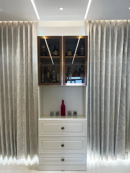 A closer look at the small bar unit, showing the warm interior lighting in the upper cabinet that highlights the collection within.