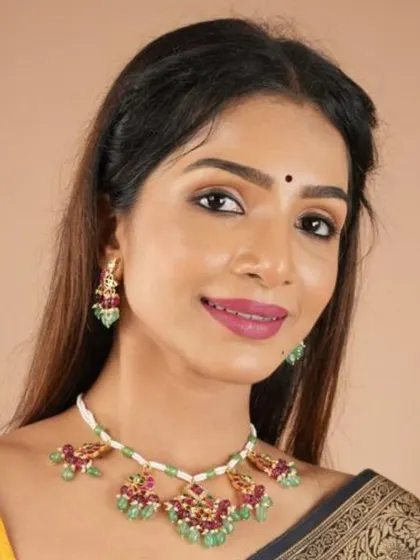 This model showcases a beautiful choker set with ruby and emerald-colored stones on a white beaded base. The matching earrings make this a vibrant and complete set for any celebration.