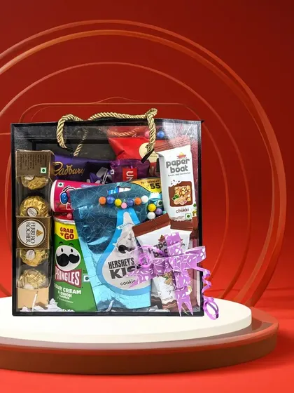 This medium-sized hamper is packed with a variety of treats, including Ferrero Rocher, Cadbury chocolates, Pringles, and more. The clear bag with a black design and purple bow makes for a stylish and abundant-looking gift.