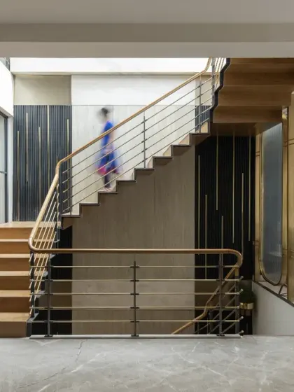The cantilevered staircase in the Screen House, crafted from wood and brass, achieves a perfect balance of warmth and sophistication, seamlessly complementing the home's modern interiors.