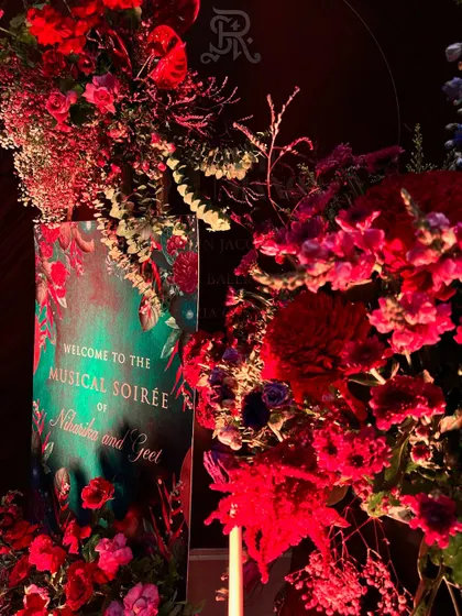 The welcome sign for a "Musical Soirée," framed by lush red flowers, sets the tone for an evening of elegance and entertainment.