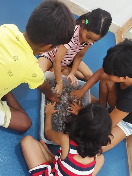 Getting hands-on with paper pulp! Kids work together to break down shredded newspaper with water, the first step in making recycled paper.