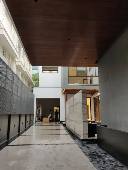 The same residential project nearing completion. Here, the finished marble flooring, wood-paneled ceiling, and stone feature wall are installed, showcasing the "after" state and the quality of the material finishes.