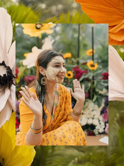A happy bride during her Haldi ceremony, framed by beautiful, oversized paper flowers.