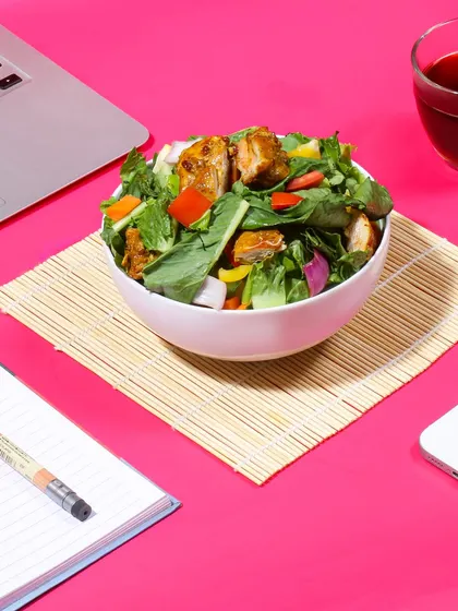 This lifestyle shot shows a healthy salad bowl in a work from home setting. It positions the food service as a perfect solution for busy professionals who want a convenient and nutritious lunch.