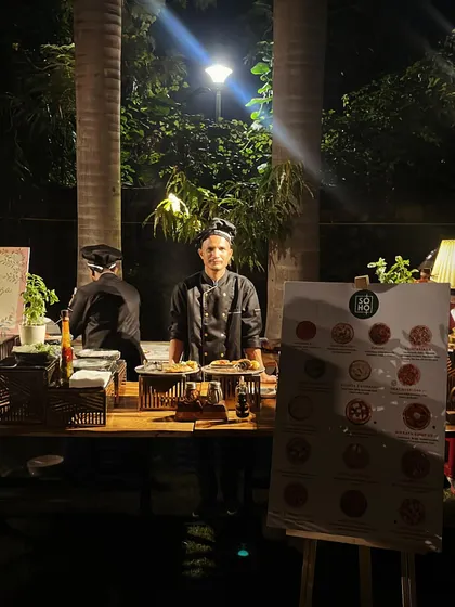 My Neapolitan pizza station set up for an evening event. The warm lighting highlights our professional setup, complete with a menu display and our team ready to serve hot pies all night.