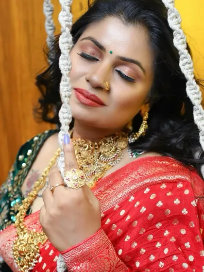 A close-up of the red Banarasi saree look, showcasing the rich gold jewelry and the detailed embroidery on the contrasting green blouse.