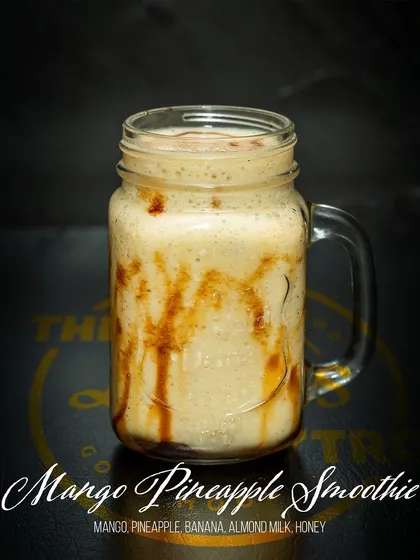 A close-up of the Mango Pineapple Smoothie, showing the rich texture and natural honey drizzle. This drink is a perfect example of our commitment to healthy indulgence.