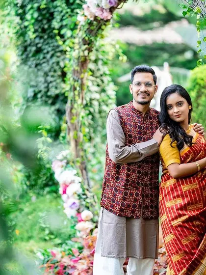 A lovely portrait of a couple framed by a floral arch and lush greenery.