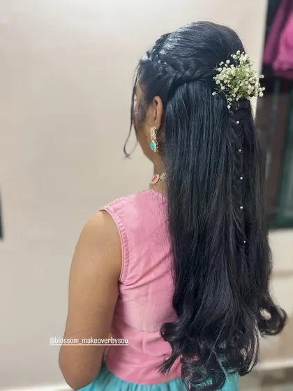 The side view shows how the braids frame the face while the rest of the hair is left in soft waves. This is a very popular style for sangeets and receptions.