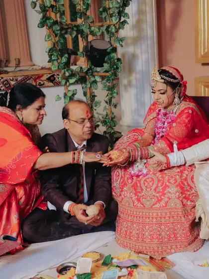 A photo of a traditional wedding ritual. The bride is seen participating in the ceremony with her parents, a moment rich with cultural significance and family connection.