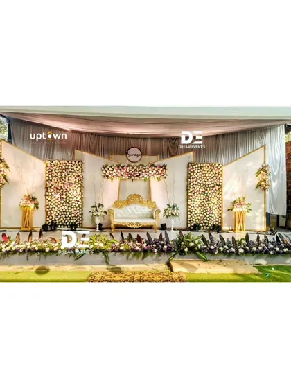 An elegant outdoor reception stage with white and gold decor.