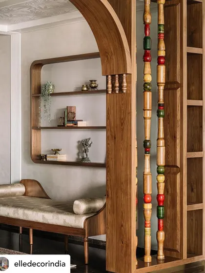This partition, featuring Channapatna pillars, separates the formal living area while maintaining an open feel. The daybed and curved shelving create a quiet nook, showcasing how traditional elements can be integrated into a modern, functional layout.