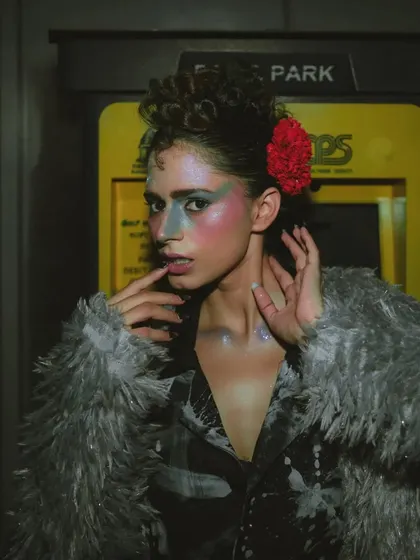 The glitter on the model's skin catches the light in this close-up, adding a touch of magic to the gritty, nighttime theme.