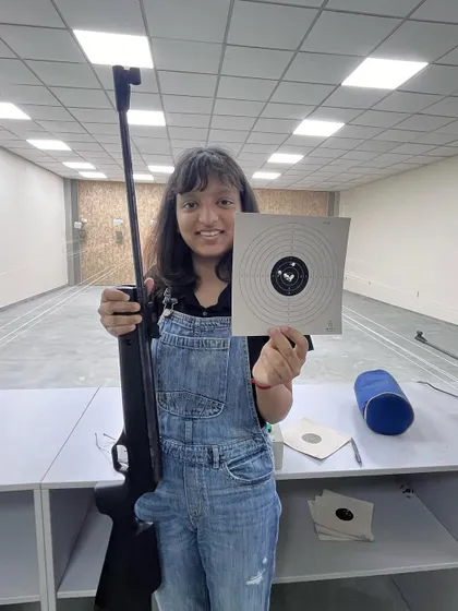 A young shooter proudly displays her target at our BS International School range. Our goal is to nurture talent from a young age and start them on their Olympic journey.